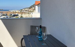 Ein Balkon mit Tisch, zwei Weingläsern und einer Weinflasche.