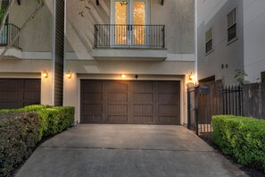 Ein Wohnhaus mit einer Doppelgarage, einem Balkon mit Geländer und einem begrenzten Auffahrt.