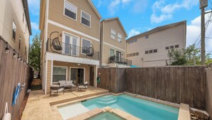 A residential property with a swimming pool, outdoor seating area, and a two-story building with a balcony. - The Wags | Sleeps 10 (Houston)