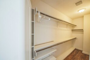 Ein begehbarer Kleiderschrank mit weißen Regalen und Holzboden.