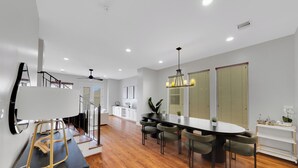 A modern kitchen with a dining area, wooden flooring, and a staircase. - The Wags | Sleeps 10 (Houston)