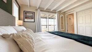Ein Schlafzimmer mit einem großen Bett, einem gerahmten Bild an der Wand und einem Fenster mit Vorhängen.