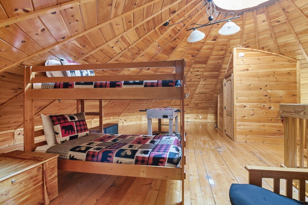 A wooden cabin with a bunk bed, a small desk, and a chair.