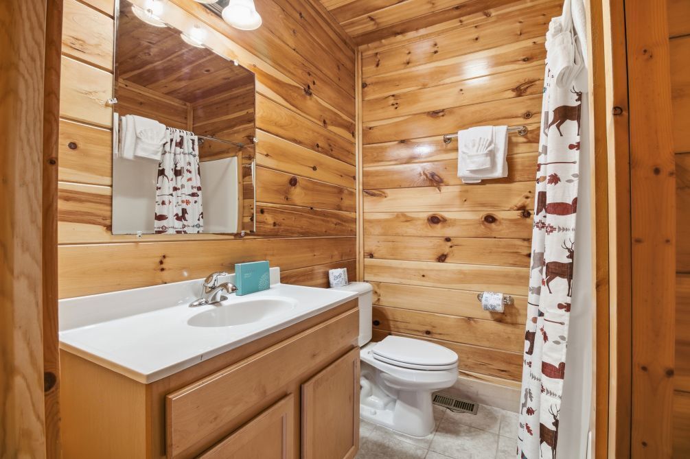 Une salle de bain aux murs lambrés, équipée d’un lavabo, d’un miroir et de toilettes.