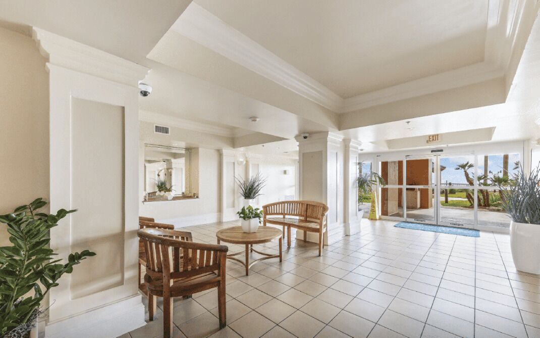 A spacious lobby with a pool area, wooden furniture, and a view of the outdoors.