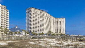 Hotel à beira-mar com vários andares, vista para a praia e faixa de areia em primeiro plano.