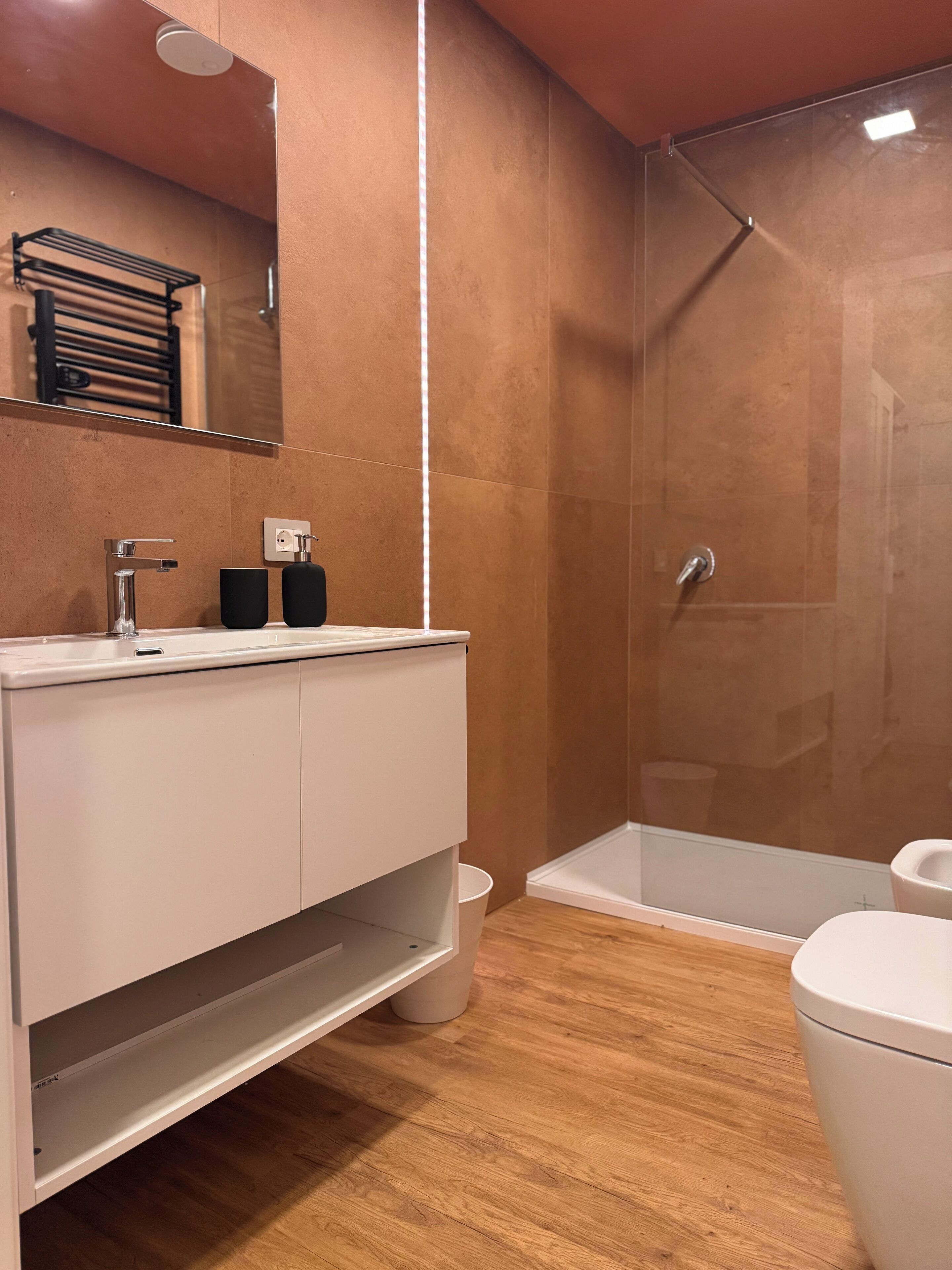 Uma casa de banho moderna com um lavatório branco, cabine de duche e sanita.