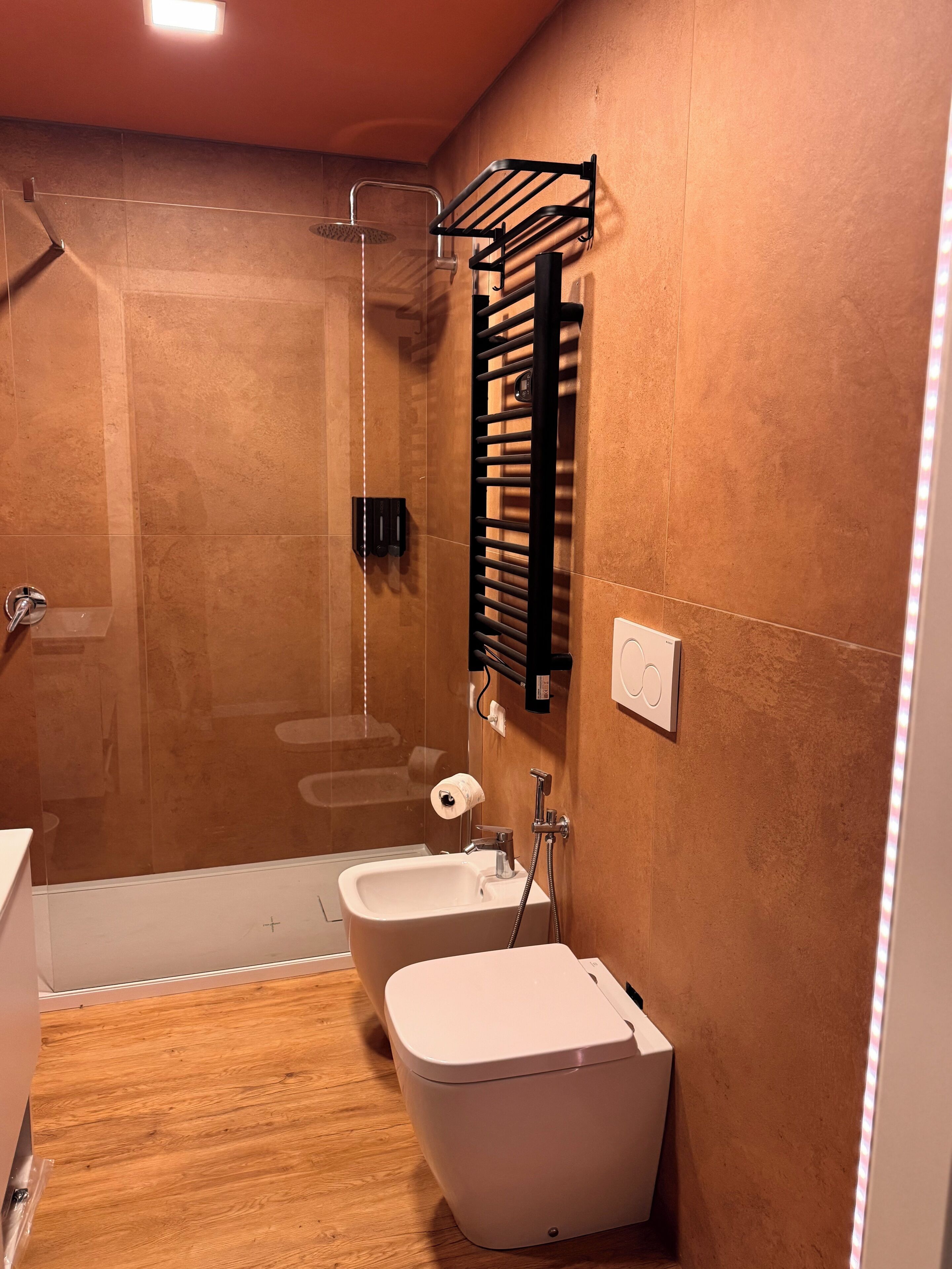 Un baño moderno con cabina de ducha de vidrio, inodoro, bidé y toallero.