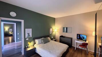 Ein modernes Schlafzimmer mit Bett, Nachttischen, Schreibtisch, Stuhl, Fernseher und einer Wanduhr.
