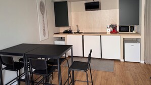 A compact kitchen with a dining area, a flat-screen TV, a microwave, and a compact refrigerator. - Le dimore di corso Torino  (Novara)