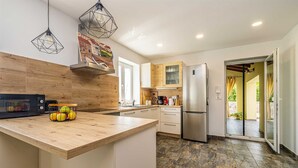 A modern kitchen with a wooden countertop, a built-in oven, a refrigerator, and pendant lights. - Holiday house MARLY with private pool (Kras)
