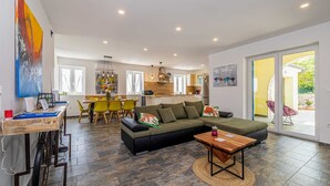 A modern living room with a sofa, a coffee table, and a dining area with chairs and a table. - Holiday house MARLY with private pool (Kras)