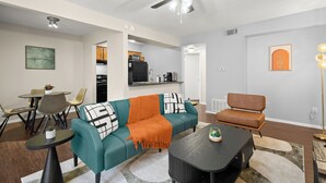 Una sala de estar moderna con un sofá color turquesa, una mesa de centro negra y un ventilador de techo.