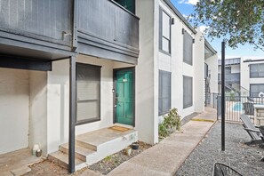 A modern building with a green door, a small front porch, and a visible staircase leading to the entrance.