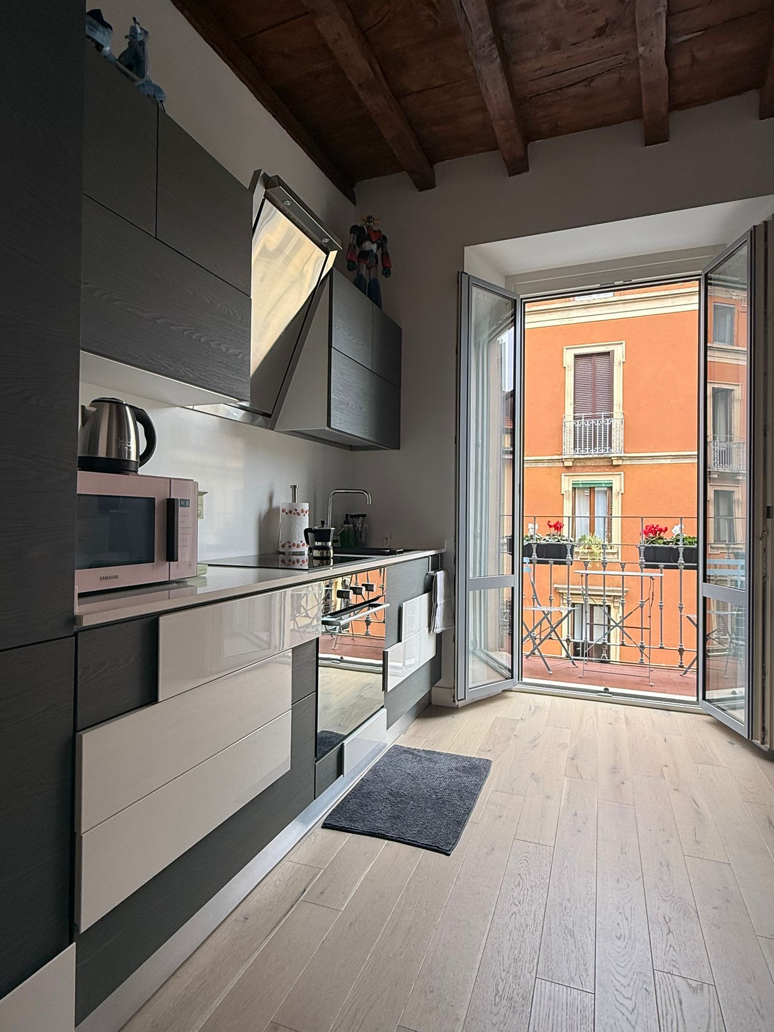 A modern kitchen with a built-in microwave, kettle, and cabinets.