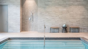 A modern indoor pool area with a tiled wall, a shower, and two small wooden benches. - Refresh and Recharge in a Clean Room Near Cedarwood Playground (Middlesex County)