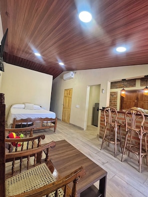 Une pièce comprenant un lit, des meubles en bois, un coin repas et une cuisine.