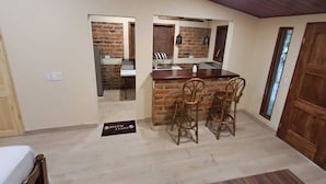 A kitchen with a brick backsplash, wooden ceiling, and a bar area with stools.