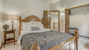 Een slaapkamer met een houten bed, een nachtkastje met een lamp en een spiegel aan de muur.
