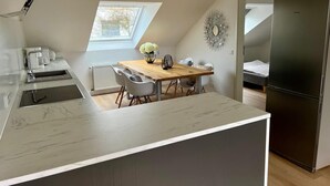 A modern kitchen with a wooden dining table, white chairs, a black refrigerator, and a skylight. - Living in Ohligs, attic apartment (Solingen)