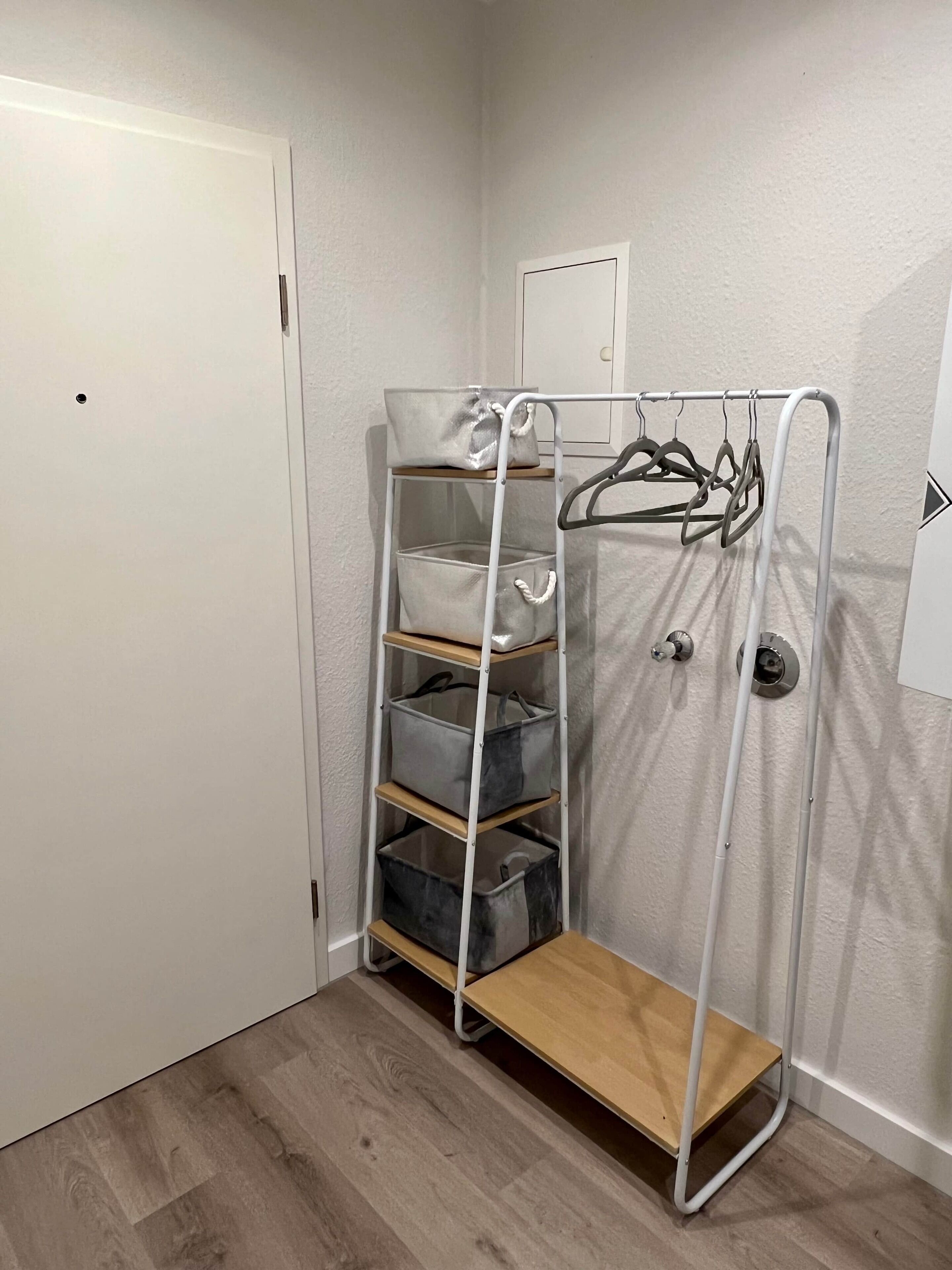 Een hoekkamer met een metalen opbergkast tegen de muur, voorzien van meerdere planken en een deur.