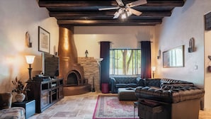 A cozy living room with a stone fireplace, leather sofa, and a ceiling fan.