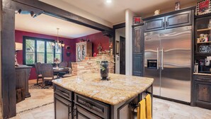 A kitchen with a granite countertop, dark cabinetry, and a stainless steel refrigerator.