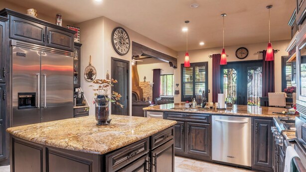 A modern kitchen with granite countertops, stainless steel appliances, and pendant lighting.