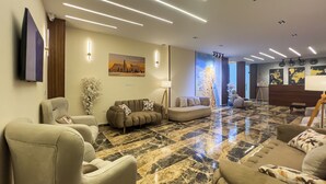 A modern living room with a marble floor, sofas, a flat-screen TV, and wall-mounted lighting. - Mazaya Pyramids View Inn (Giza)