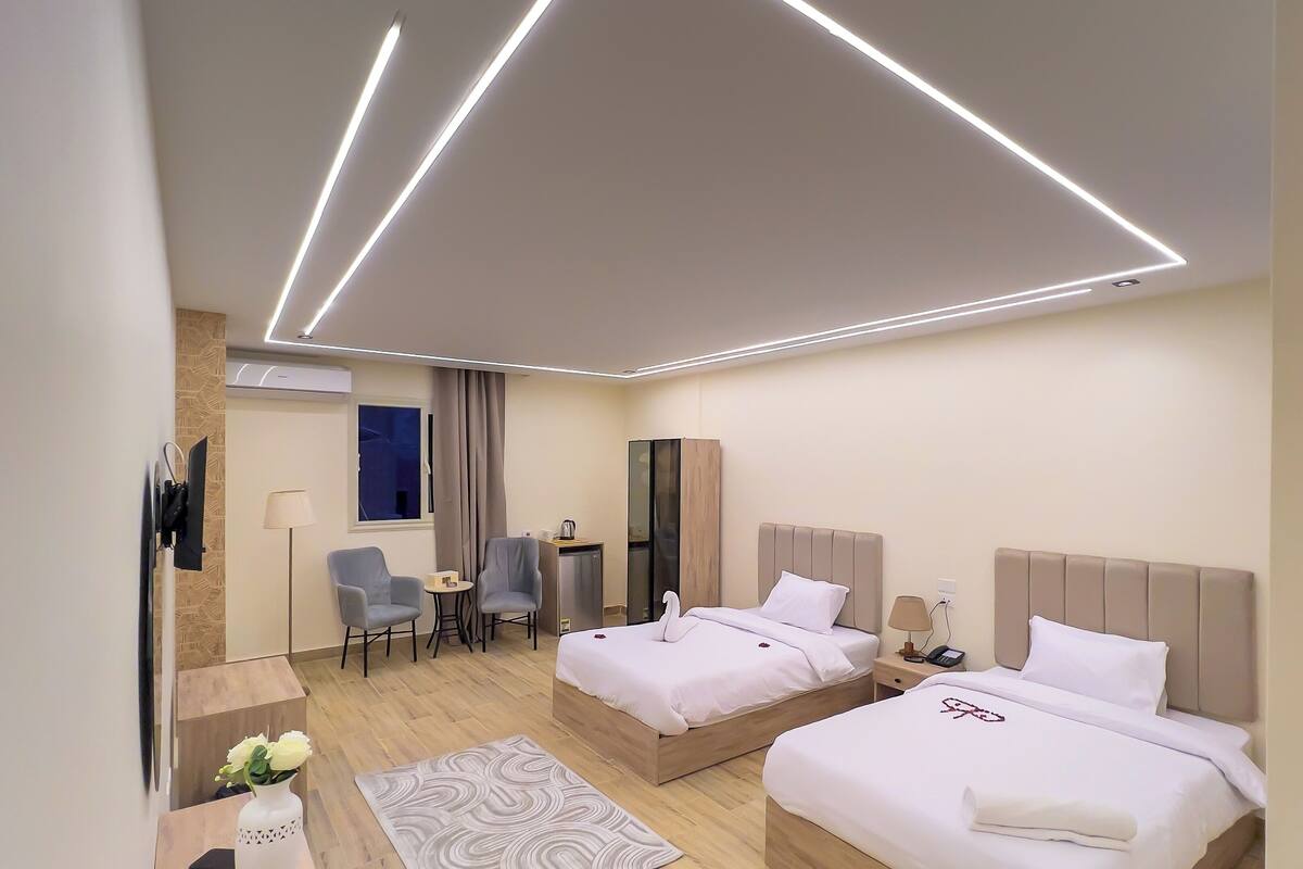 Una habitación de hotel moderna con dos camas, un escritorio, una silla y una mesita.