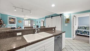 A modern kitchen with a granite countertop, white cabinets, and a built-in dishwasher. - Two Bedroom Updated Condo with Great Amenities (Ocean City)