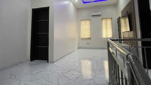 A spacious room with a marble floor, a black door, and a staircase with a metal railing. - Oral Estate Lekki, Chevron, Executive 4bed ensuite duplex. (Lagos)