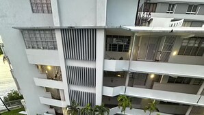 Ein mehrstöckiges Hotel mit Balkonen, einem Pool und üppiger Bepflanzung.