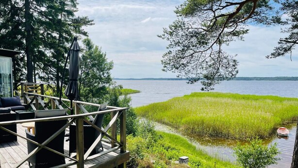 Une terrasse dotée de mobilier d’extérieur, offrant une vue sur un lac et des zones humides.