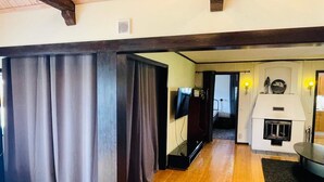 Une pièce avec un plancher en bois, une télévision, une cheminée et un rideau.