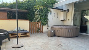 A patio with a hot tub, a wooden bench, and a small trash bin. - Cozy apartment just minutes from the beautiful Mondello beach. (Palermo)