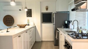 A modern kitchen with white cabinetry, a built-in stove, a refrigerator, and pendant lighting. - Beautiful Apartment in los Cocos Santa Marta 1 (Santa Marta)