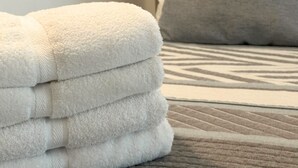 A neatly folded stack of white towels on a bed with a patterned bedspread. - Beautiful Apartment in los Cocos Santa Marta 1 (Santa Marta)