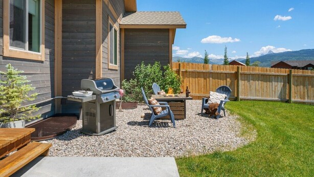 A backyard with a barbecue grill, two Adirondack chairs, and a small fire pit. - Perfect Basecamp for Outdoor Fun (Driggs)