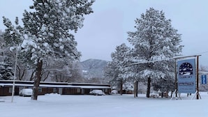Un motel enneigé, avec une enseigne indiquant « Dark Sky River Lodge », et une vue sur les montagnes en arrière-plan.