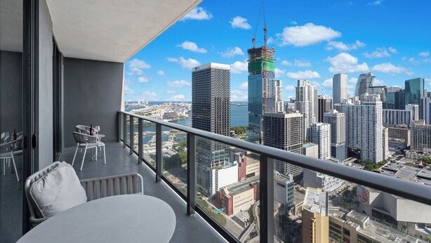 Ein Balkon mit Blick auf eine Stadtlandschaft, darunter Wolkenkratzer und ein Wasserufer.