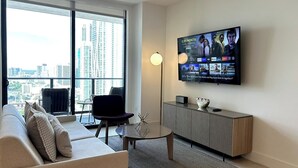 Ett modernt vardagsrum med en stor TV, en soffa, en fåtölj och ett soffbord.
