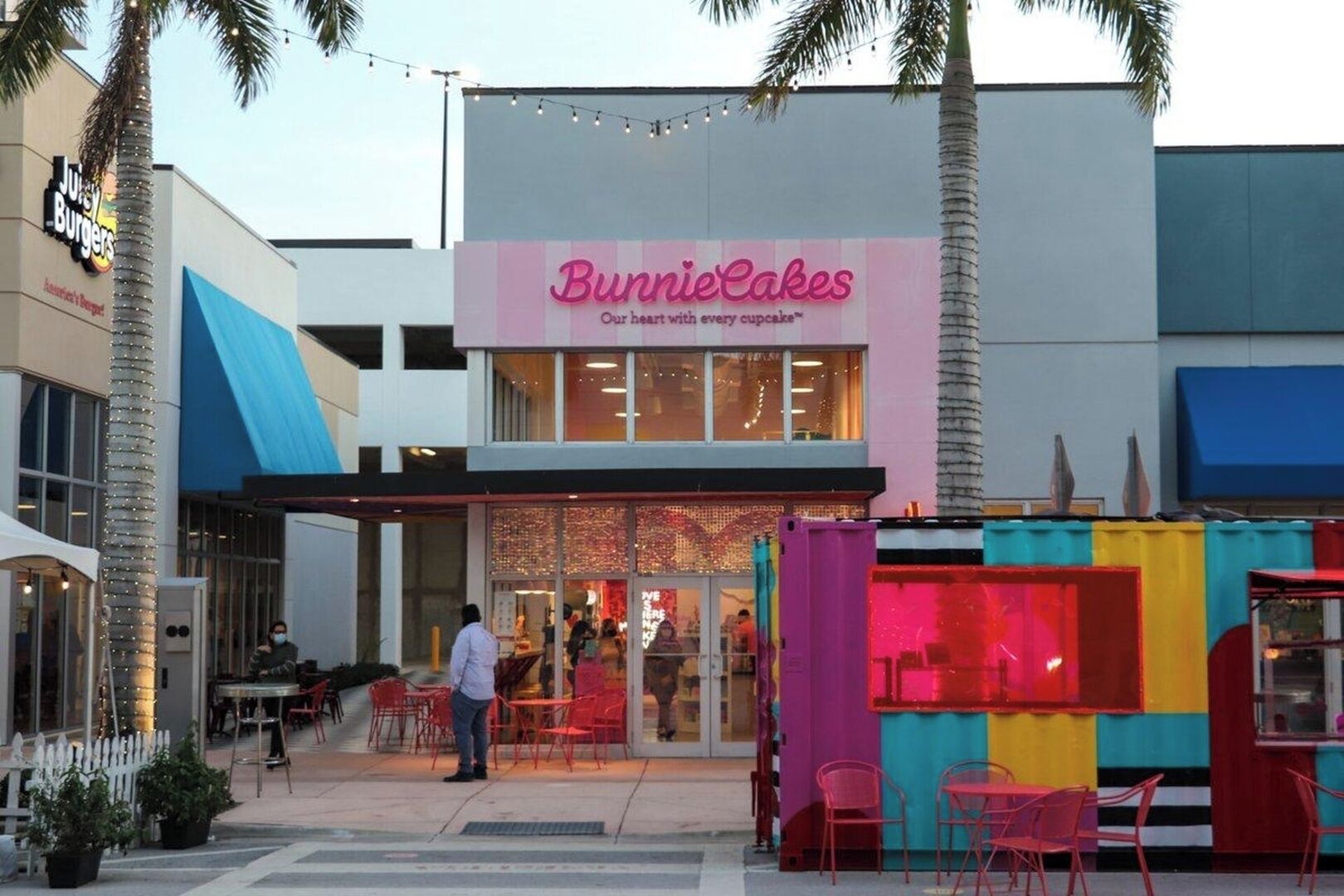 A storefront with a sign reading "Bunnie Cakes" and a colorful outdoor seating area.