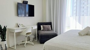 Una camera d'albergo con un letto, una scrivania con una sedia, una televisione e una finestra con tende.