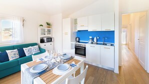 Un espacio habitable compacto con comedor, kitchenette y sofá con cojines estampados.