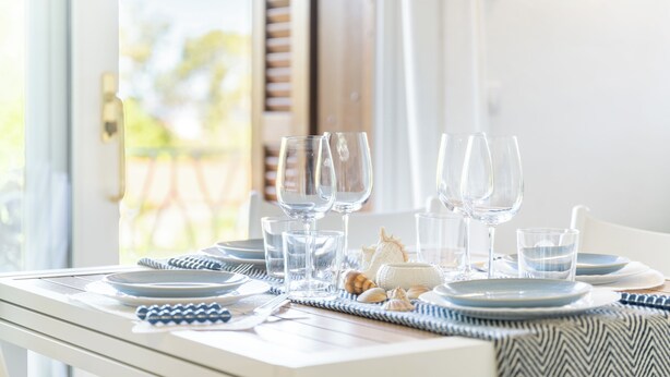 Una mesa lista para comer, con platos, vasos y un mantel individual.