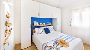 Un dormitorio con cama, armario y ventana con cortinas.