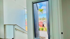 Ett rum med ett stort fönster, en trappa och utsikt över ett bostadsområde.