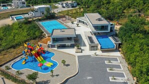 Un resort moderno con piscina, área de juegos para niños y estacionamiento.