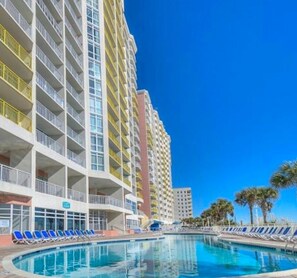 A hotel with a pool area, multiple balconies, and a clear blue sky. - Bay Watch Resort Oceanfront Condo (North Myrtle Beach)